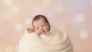 Śpiący noworodek chłopiec owinięty w kremowy kocyk ze złotą koroną symbolizujący popularność imienia Leon jako piątego najpopularniejszego imienia dla chłopców w Polsce